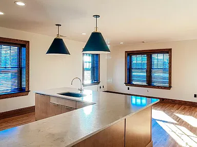 Kitchen island with a sink under two pendant lights, with windows beyond